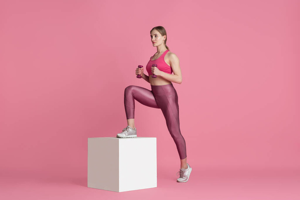 Beautiful young female athlete practicing on pink studio background, monochrome portrait - Fotoğraf, Görsel