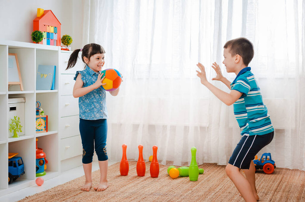 ネイティブの子供の男の子と女の子が子供のゲームルームで遊んでボールを投げます。相互作用の概念兄弟、コミュニケーション、相互作用、相互作用、隔離、隔離された家、兄弟姉妹. - 写真・画像