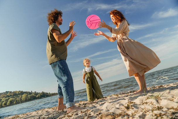 Happy family playing with ball on the beach at the day time. - Photo, image