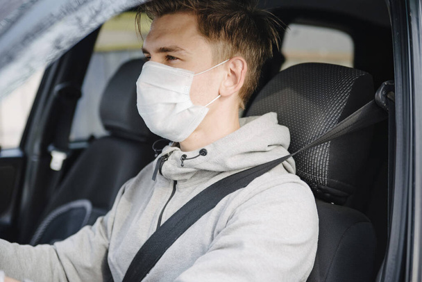 Mies ajaa autoa suojaava naamio ja käsineet.Ehkäisy sepelvaltimotauti.Suojatoimenpiteet vastaan coronavirus, covid-19
 - Valokuva, kuva