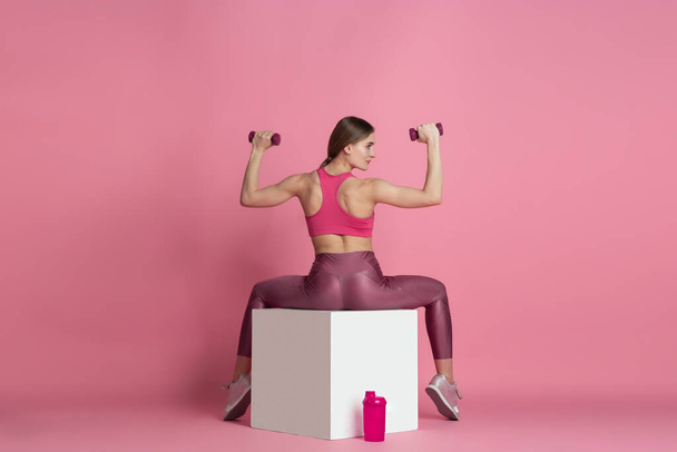 Beautiful young female athlete practicing on pink studio background, monochrome portrait - Valokuva, kuva