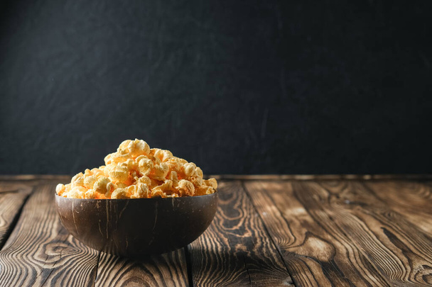 Cheesy popcorn in a coconut bowl on a rustic background copy space. - Фото, изображение