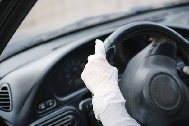 Female driver in a mask and gloves holding the steering wheel, close-up.Prevention of coronavirus infection.Protective measures against coronavirus, covid-19 - Valokuva, kuva