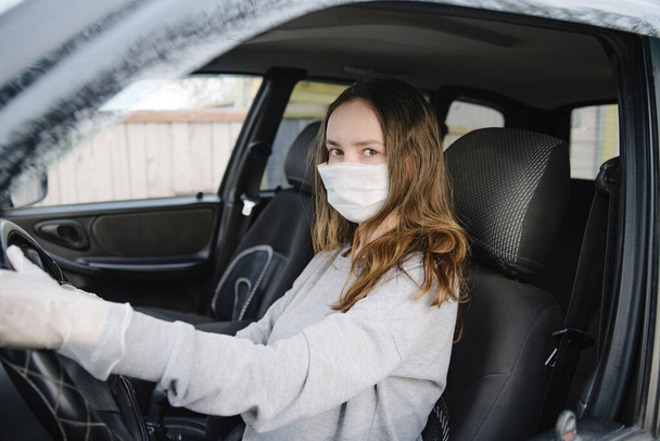 Nainen ajaa autoa suojaava naamio ja käsineet.Ehkäisy sepelvaltimotauti.Suojatoimenpiteet vastaan coronavirus, covid-19
 - Valokuva, kuva