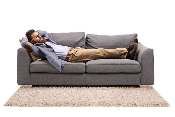 Bearded man resting on a couch after work isolated on white background - Fotó, kép