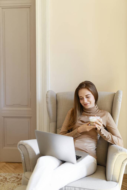 Young lady sitting on armchair. Home office. - 写真・画像