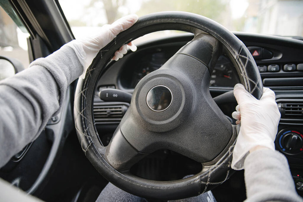 Female driver in a mask and gloves holding the steering wheel, close-up.Prevention of coronavirus infection.Protective measures against coronavirus, covid-19 - Foto, Imagen