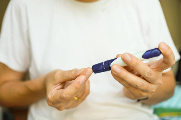 lähikuva miehen käsissä käyttäen Lancet sormella tarkistaa verensokeri glukoosimittarilla makuuhuoneessa aamulla. Käyttö lääkkeenä, diabetes, glykemia, terveydenhuolto ja ihmisten käsite
. - Valokuva, kuva