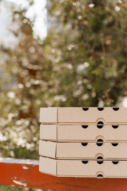 Promotie van 2 + 2 pizzadoos voor voedsellevering. Geïsoleerde verticale foto van 4 kartonnen pizzadozen met lege plaats links voor tekst. Veilige koerier bezorging van restaurant. Stop het coronavirus - Foto, afbeelding
