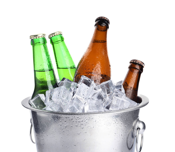 Secchio in metallo con bottiglie di birra e cubetti di ghiaccio isolati su bianco - Foto, immagini