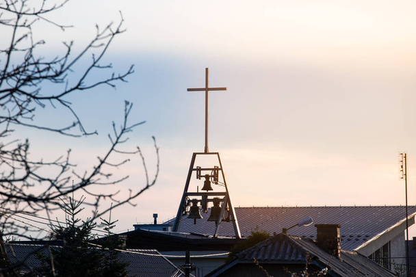 Крест с колокольчиками на ясном голубом небе, религиозная концепция
 - Фото, изображение