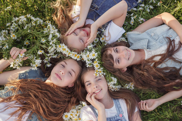 Widok z góry urocze długowłose nastolatki leżące na zielonej trawie w słoneczny letni dzień, i patrząc w aparat z uśmiechem lub snem. Koncepcja i idea szczęśliwego dzieciństwa - Zdjęcie, obraz