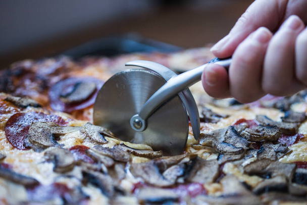 Foto di una persona che taglia una pizza
 - Foto, immagini
