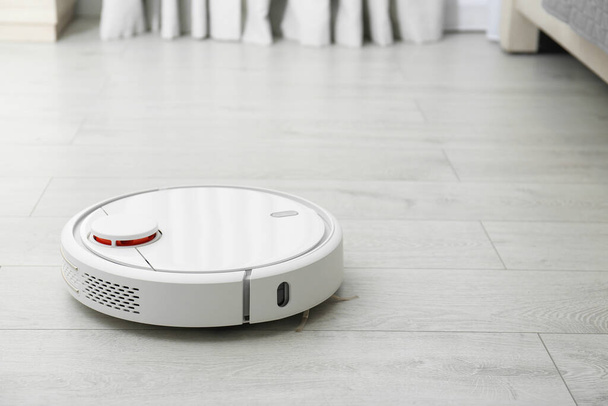 Hoovering floor with modern robotic vacuum cleaner indoors. Space for text - Foto, immagini