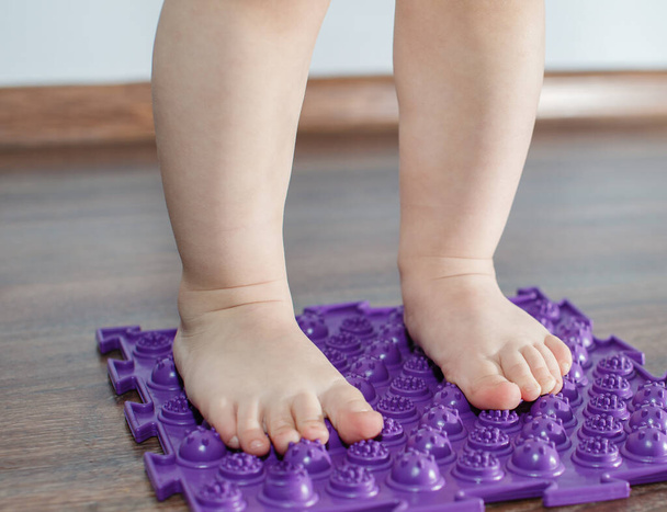 Feet of small baby on a orthopedic mat carpet rug - Photo, Image
