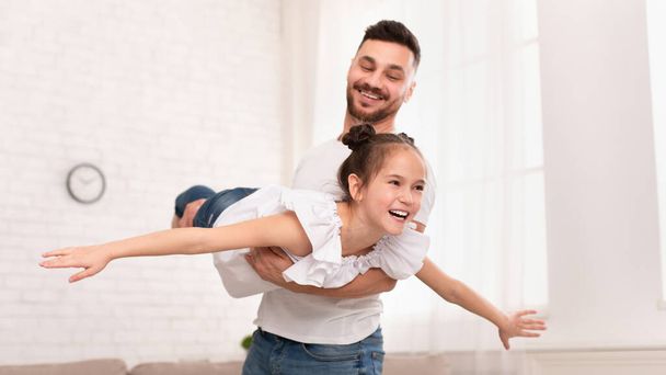 Onnellinen isä kantaa tytärtään kuin lentokone, panoraama
 - Valokuva, kuva