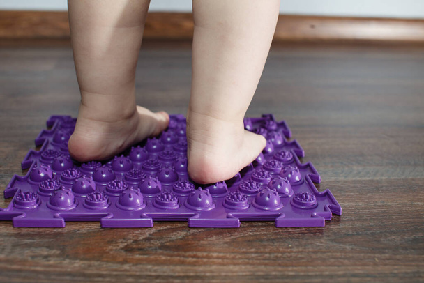 Füße eines kleinen Babys auf einem orthopädischen Teppich - Foto, Bild