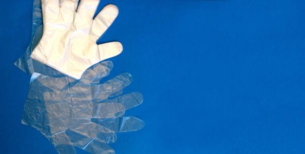 COVID-19. Coronavirus. Coronavirusinfectie. Wegwerp latex handschoenen op een blauwe achtergrond. Bescherm je gezicht en handen tegen het virus. Ruimte voor tekst - Foto, afbeelding
