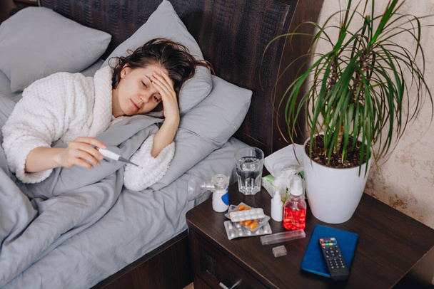 Молодая больная женщина в постели пьет таблетки. копировальное пространство
 - Фото, изображение