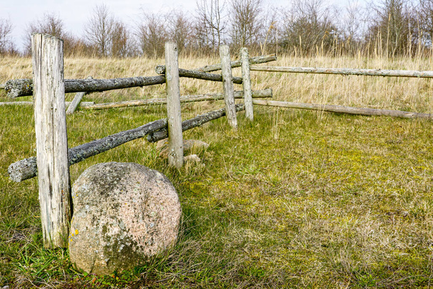 前景に大きな石がある田園地帯のパドックの美しい古い木製の柵 - 写真・画像