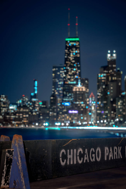 Un gros plan d'une barricade en bois bleu altéré du Chicago Park District avec l'horizon de la ville et des lumières hors foyer bokeh en arrière-plan faisant une belle scène de paysage urbain ou toile de fond
. - Photo, image