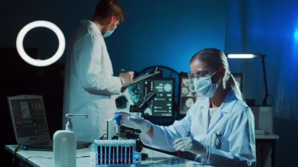 Wissenschaftler und Student arbeiten im Labor. Doktor lehrt Praktikant, Blutanalysen durchzuführen. Laborwerkzeuge: Mikroskop, Reagenzgläser, Geräte. Coronavirus, Impfstoffforschung, Bakteriologie - Filmmaterial, Video