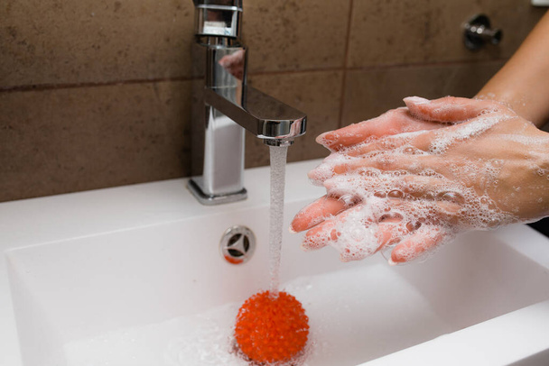 Female hands holding a myofascial ball as the concept of coronavirus infection. Washing hands with antibacterial soap - Photo, Image