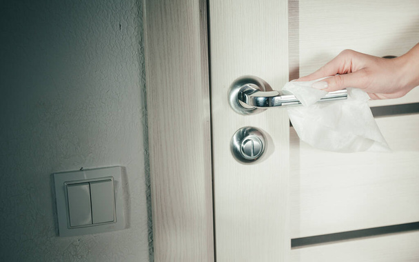 Women hand wipes cloth chrome door handle with latch. The door and door handle closeup. - Photo, Image