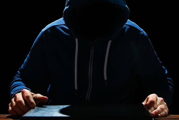 Hacker with laptop sits at a table and abstract binary code. Business life threat virtual programs. - Фото, зображення
