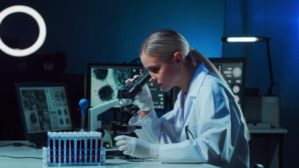 Ženská vědkyně pracující v moderní laboratoři. Doktor dělá mikrobiologický výzkum. Laboratorní nástroje: mikroskop, zkumavky, vybavení. Koronavirová covid-19, bakteriologie, virologie, DNA a zdravotní péče - Záběry, video