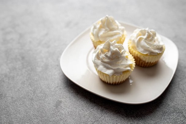Three mini Cheesecakes with whipped cream icing on a white plate - Foto, Imagem