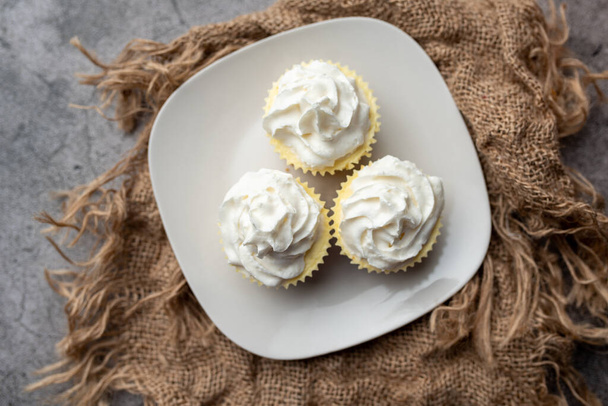Three mini Cheesecakes with whipped cream icing on a white plate - Fotó, kép