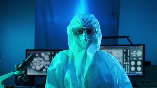 Naukowiec w kombinezonach ochronnych i maskach pracujących w laboratorium badawczym przy użyciu sprzętu laboratoryjnego: mikroskopów, probówek. Koronawirus covid-19 zagrożenie, odkrycie farmaceutyczne, bakteriologia i wirusologia - Materiał filmowy, wideo
