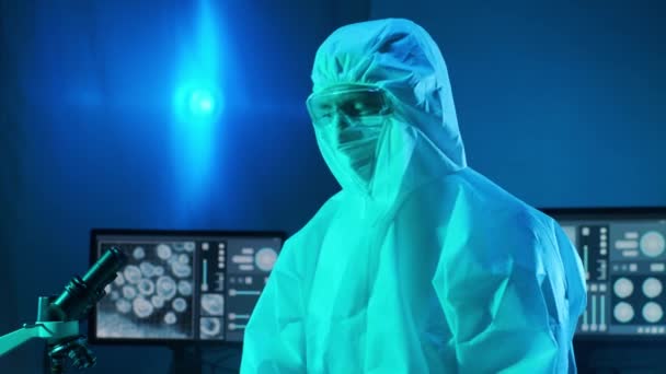 Вчений в захисному костюмі і масках, що працюють в дослідницькій лабораторії, використовуючи лабораторне обладнання: мікроскопи, тестові трубки. Коронавірус SARS-CoV-2 небезпеки, фармацевтичні відкриття, бактеріологія і вірологія - Кадри, відео