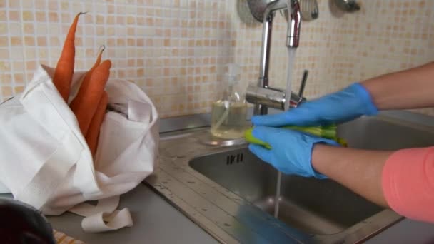 Blisko żeńskiej dłoni w rękawiczkach medycznych myje cukinię w domu w kuchni podczas epidemii koronawirusów, by chronić się przed zakażeniem wirusem covid-19. Samoizolacja podczas kwarantanny - Materiał filmowy, wideo