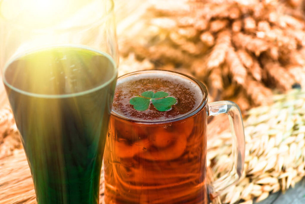 Μια κανάτα ελαφριά μπύρα και μια πράσινη ιρλανδική μπύρα από κοντά την ημέρα του Πάτρικ. Μπύρα σε γυάλινο κοντινό πλάνο - Φωτογραφία, εικόνα