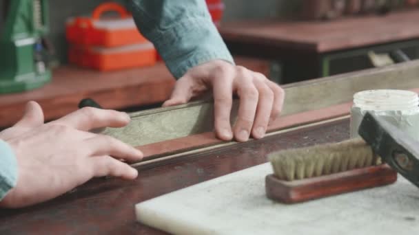 Gros plan de tanneur professionnel met de la pâte sur une ceinture en atelier. Processus de travail de la ceinture en cuir dans l'atelier de cuir
. - Séquence, vidéo
