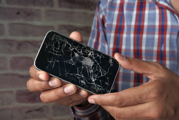 Close-up van de man hand houden gebroken smartphone  - Foto, afbeelding