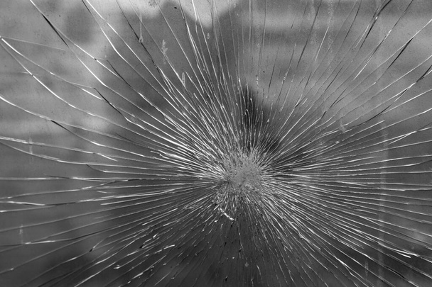Broken old car glass in cracks diverging in different directions. Close up  Black and white image. - Photo, Image