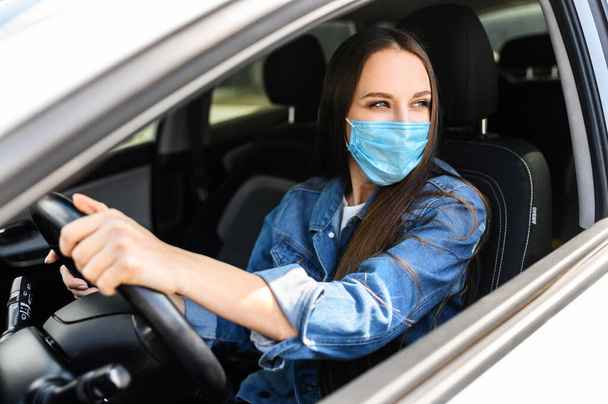 Young woman in protective mask is driving car - Foto, Bild