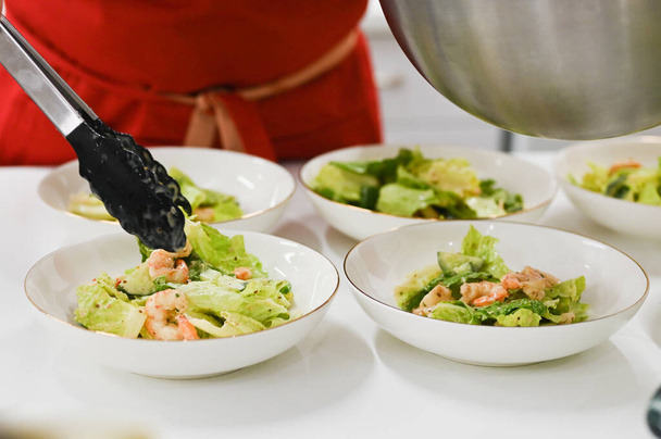 le cuisinier étale la salade cuite. nourriture végétarienne. cuisinier dans la cuisine
 - Photo, image