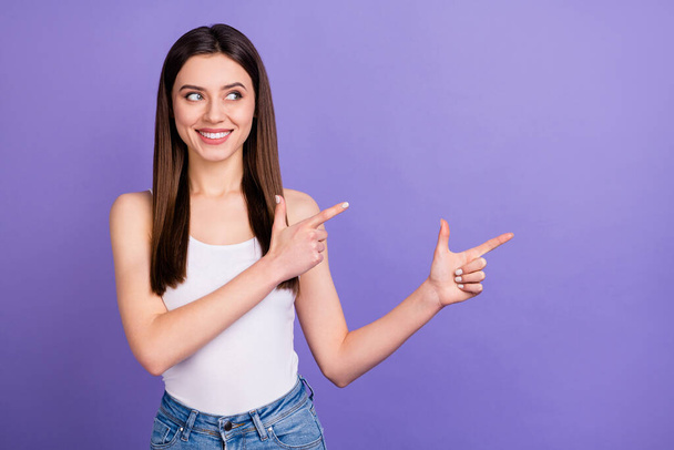 Portrait of positive cheerful girl promoter point index finger copyspace demonstrate ads promo recommend suggest select wear modern clothes isolated over violet color background - Foto, imagen