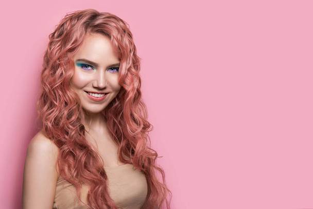 Mulher loira bonita sorridente com cabelo pastel rosa brilhante encaracolado. Penteado ondulado, espaço de cópia para o seu texto
 - Foto, Imagem