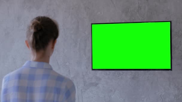 Zöld képernyő koncepció - nő néz lapos intelligens led TV zöld kijelzővel - Felvétel, videó