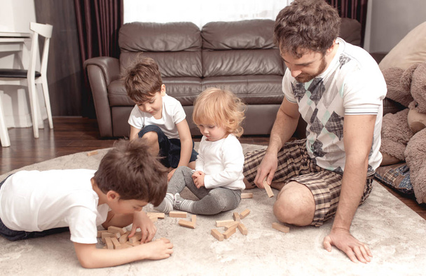 Χαρούμενη οικογενειακή ιδέα. Ο πατέρας μένει σπίτι και παίζει με τα παιδιά. Διακοπές μαζί με την οικογένεια διασκεδάζοντας. - Φωτογραφία, εικόνα