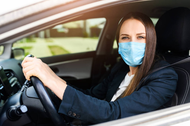 Young woman in protective mask is driving car - Fotó, kép