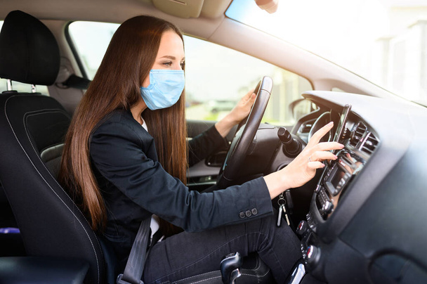 Young woman in protective mask is driving car - Fotoğraf, Görsel