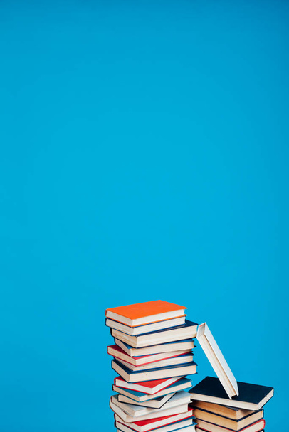 wiele stosów książek edukacyjnych w bibliotece uniwersyteckiej na niebieskim tle - Zdjęcie, obraz