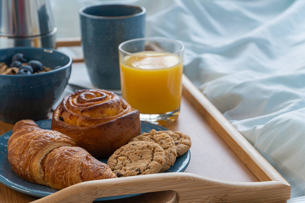 Śniadanie serwowane w łóżku na drewnianej tacy z kawą i rogalikami. Pojęcie "dzień dobry" - Zdjęcie, obraz