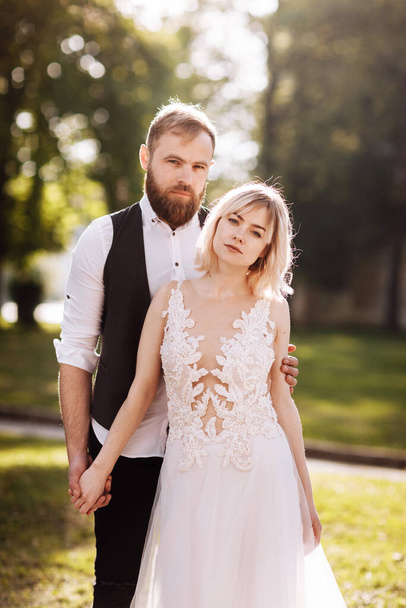 Glückliches Ehepaar in einfachen Brautkleidern. Hochzeitspaar. Stilvolles Brautpaar. Stilvolles weißes Kleid auf der Braut. Ehekonzept - Foto, Bild